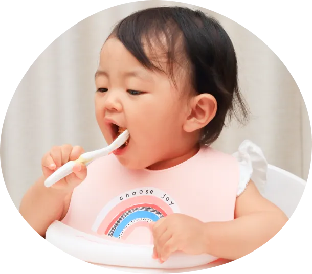 自分でスプーンを持ってご飯を食べている子どもの写真