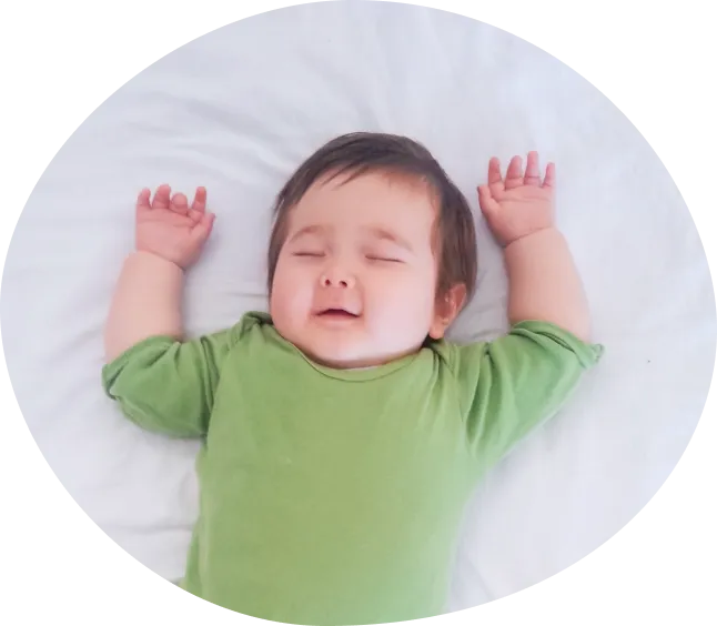 両手をあげて微笑みながら眠る赤ちゃんの写真